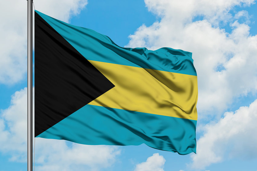 flag of the bahamas flying against a blue sky with clouds