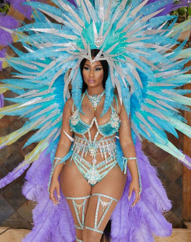 nicki minaj is wearing a blue and purple carnival costume with several plumes of feathers attached to the bikini style two piece jewel covered costume