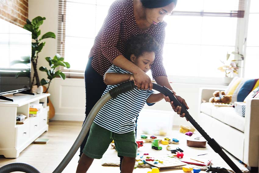 black mother helping son vacuum